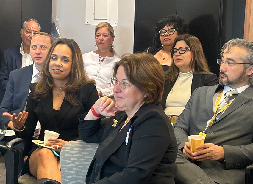 Group of professionals seated and engaged in discussion at an Optimus Health Care community or board meeting event.
