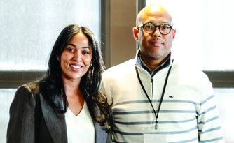 Two Optimus Health Care staff members smiling together indoors at a professional event